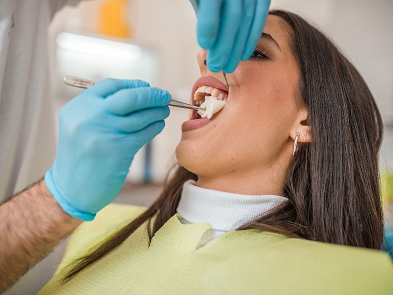 Dentist in blue gloves performing a tooth extraction on a patient in Warrenville, IL