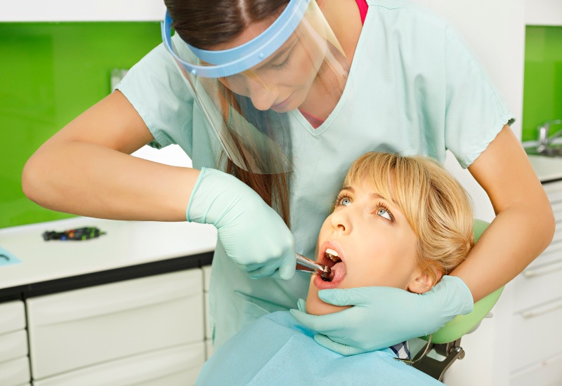 Dentist performs tooth extraction on a patient in a dental clinic in Warrenville, IL